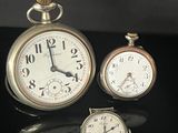 three different types of pocket watches sitting on a black surface