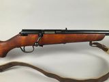 a rifle with a wooden barrel and a leather strap