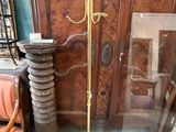 un grand lampadaire en laiton à côté d'un grand meuble en bois