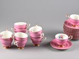 a lot of pink cups and saucers sitting on a table