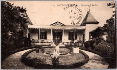 une vieille photo d'une maison avec une fontaine devant