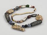 un gros plan d'un collier posé sur une surface blanche, orné de perles