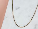 un collier à chaîne en or posé sur une surface en marbre