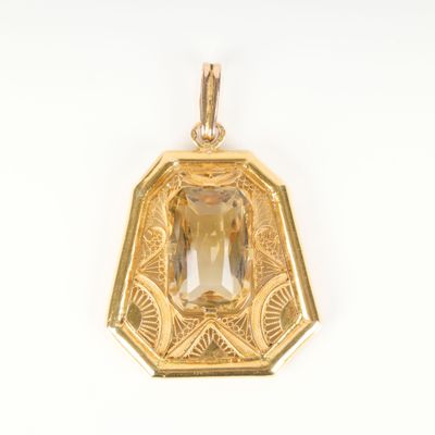 a close up of a yellow gold pendant with a faceted green stone