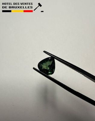 a close up of a pair of tongs holding a green tourmaline