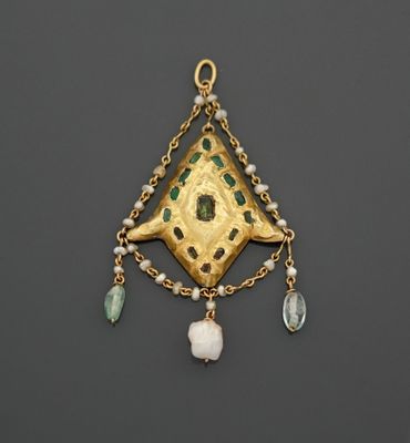 un gros plan sur un pendentif en or orné de perles vertes et blanches