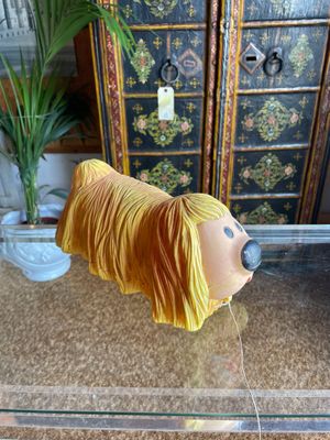 a yellow dog statue on a glass table next to a potted plant
