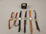 plusieurs montres différentes et un présentoir à montres posés sur une table