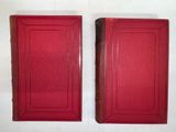 two red books sitting on top of each other on a white surface