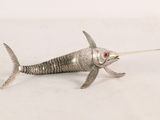 silver fish figurine with red eyes sitting on a white surface