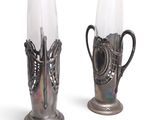 two silver vases that are next to each other