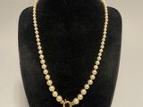 un collier de perles muni d'un fermoir en or, posé sur un mannequin