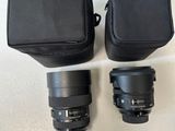 two camera lenses and a case on a white surface