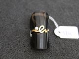 une bague sur laquelle est gravé un nom, posée sur une table