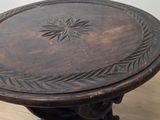 a wooden table with a carved top on a hard wood floor