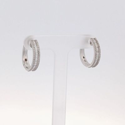une paire de boucles d'oreilles créoles en diamant posées sur un présentoir transparent
