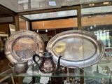 une vitrine en verre contenant des assiettes en argent et une théière en argent