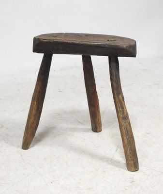 an old wooden stool with two wooden legs on a white surface