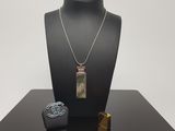 un collier, un bracelet et un briquet exposés sur une table noire