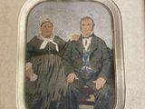 an old picture of a man and woman sitting on a chair