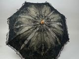un parapluie en dentelle noire avec un manche en bois sur fond blanc