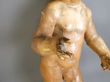 une petite statue représentant un bébé tenant un morceau de bois