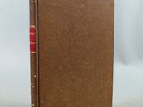 a brown book with a red cover sitting on top of a white surface