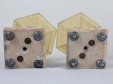 pair of dices with holes and rivets on them sitting on a white surface