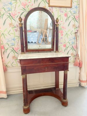 un miroir posé sur une table dans une pièce au papier peint à motifs floraux