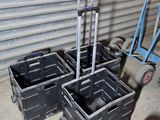 three black plastic containers with wheels and a hand truck