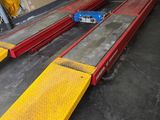 des rampes jaunes et rouges dans un entrepôt, avec une voiture bleue en arrière-plan