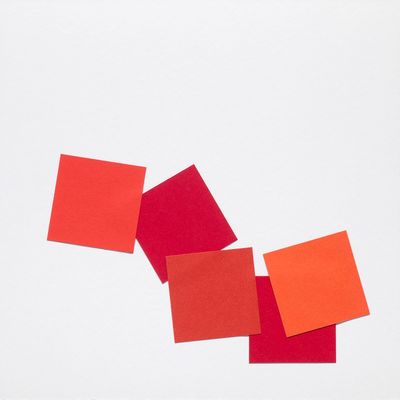 four squares of red and orange colored paper on a white surface