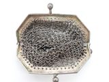 an old silver purse with a chain around it on a white surface