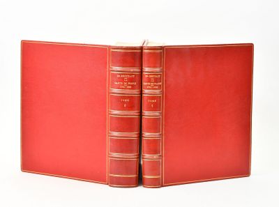 deux livres rouges sont ouverts sur une surface blanche