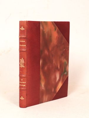 un vieux livre à la couverture rouge posé sur une surface blanche