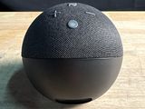 a close up of a black google home speaker on a wooden table