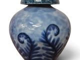un vase bleu et blanc muni d'un couvercle, posé sur une surface blanche
