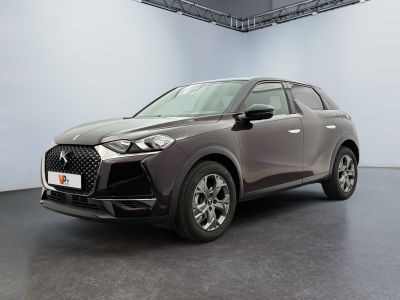 Une voiture grise est garée dans une grande pièce au sol noir.