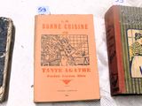 Trois livres sont alignés sur une table recouverte d'une nappe blanche.