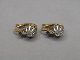 two pairs of gold and diamond earrings on a gray surface
