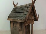 a small wooden birdhouse with two birds on top of it