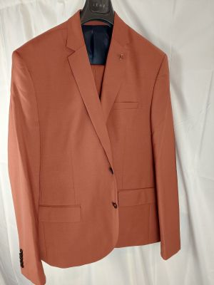 un blazer orange suspendu à un cintre sur fond blanc