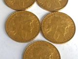 six gold sovereigns are arranged in a row on a white surface