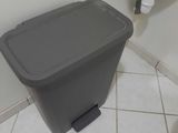 a trash can sitting in the corner of a bathroom