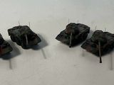 four small toy tanks are lined up on a white surface