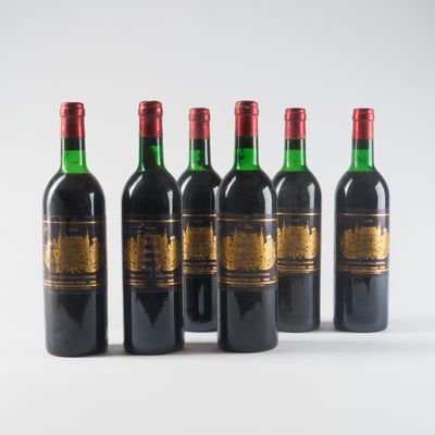 six bouteilles de vin sont alignées sur une surface blanche