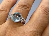 la main d'une femme tenant une bague sertie d'une pierre bleue