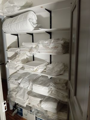 a closet filled with lots of white sheets and blankets