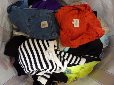 a pile of clothes in a laundry basket on a bed