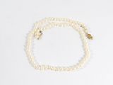 un collier de perles blanches avec un fermoir en or et un fermoir en or